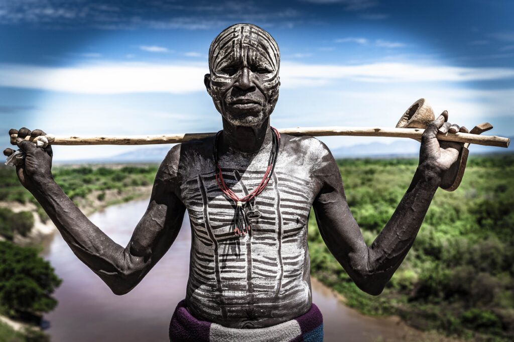 A man with painted face holding a stick.