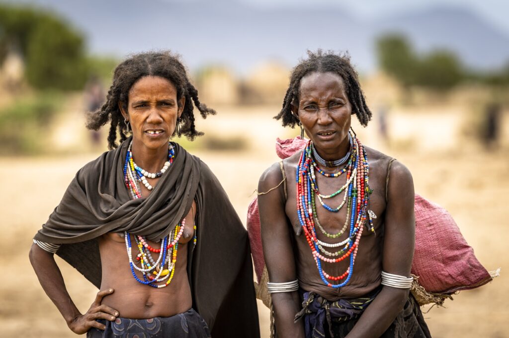 Two women with long hair and necklaces on their necks.