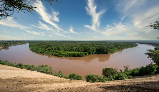 A river with trees in the background and clouds above.